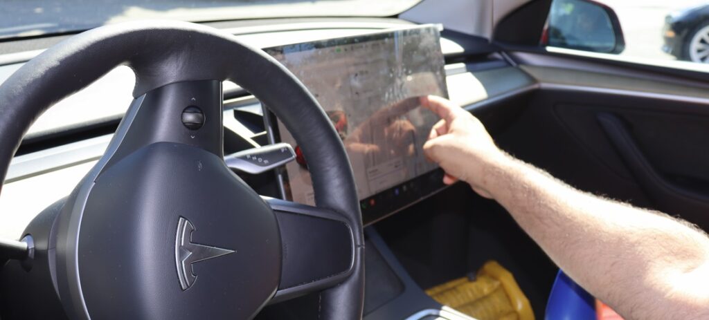 Tesla car driver uses display screen to find supercharger.